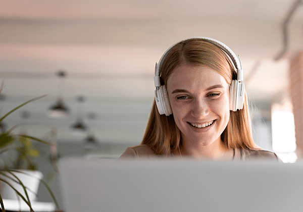 Chica con casos sonriendo frente a un ordenador portátil